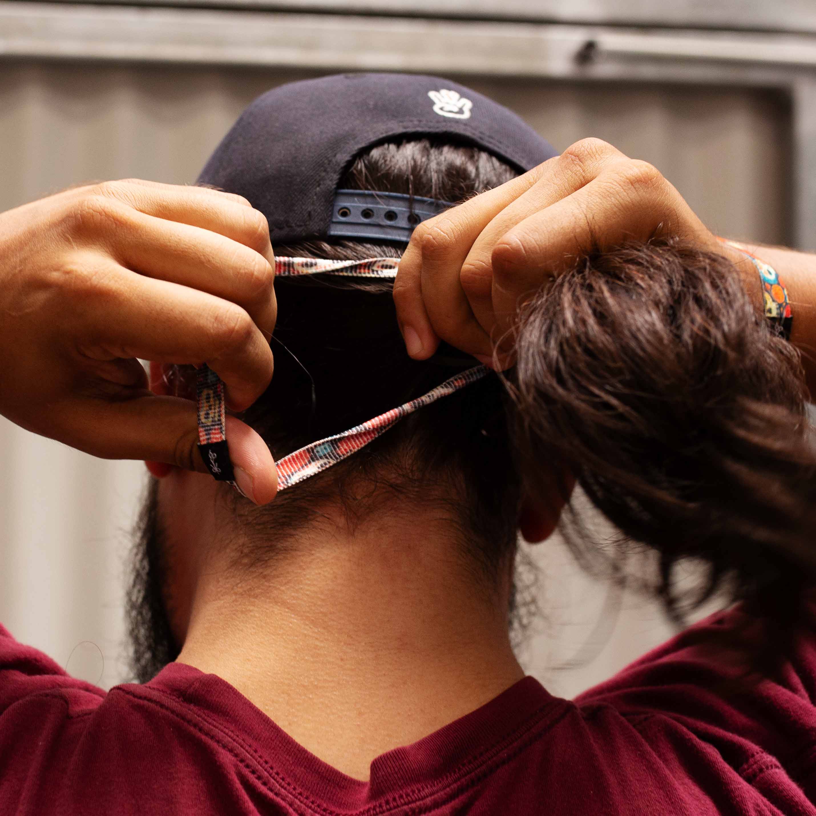 A long hair man tying his hair with a Longhairs hair ties