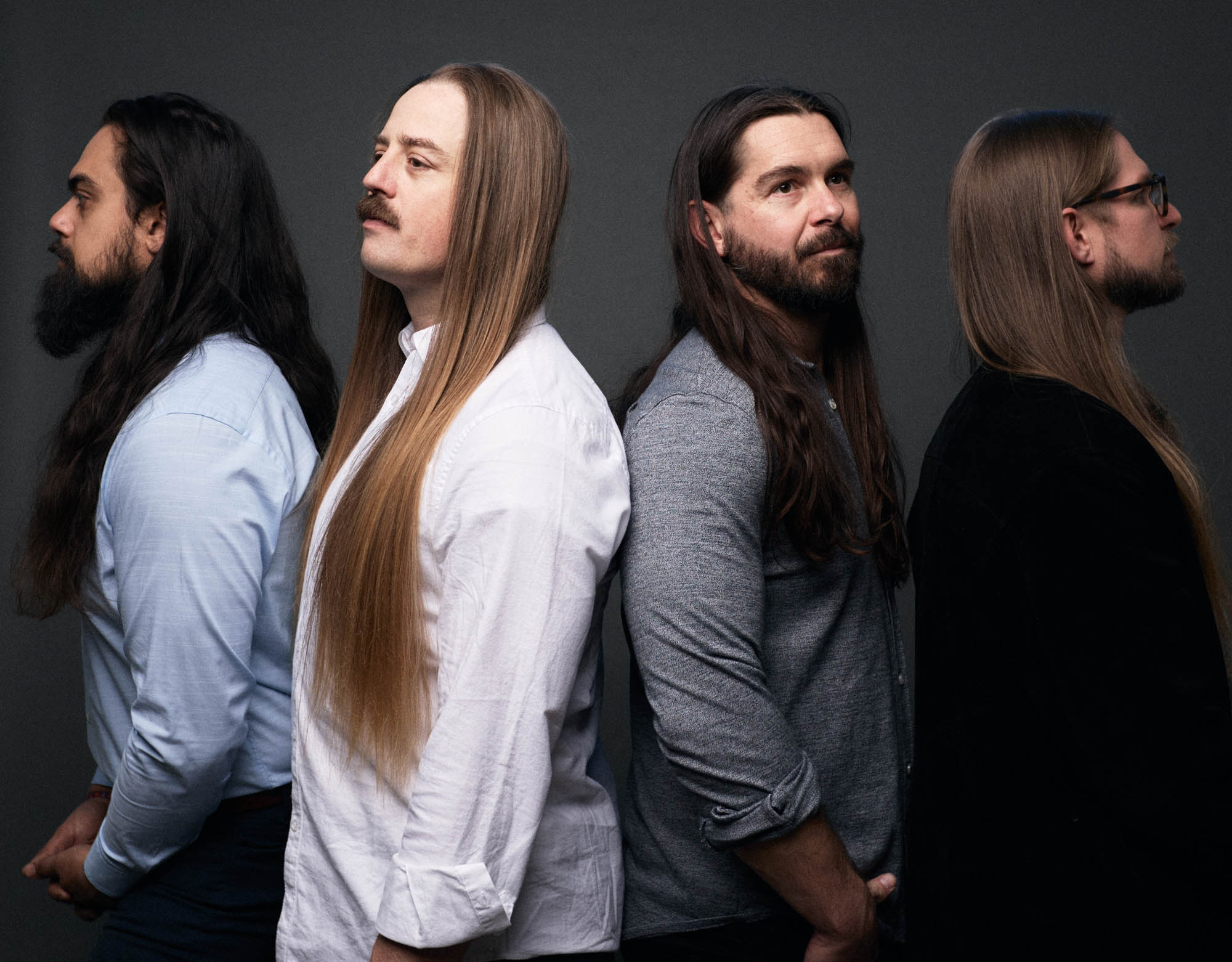 Jose Mejia and Chris Healy looking left, Lindsay Barto and Sean Horton looking right, standing in a line, in casual wear, in a studio, each looking off to the side. By Erica Joan 2024.