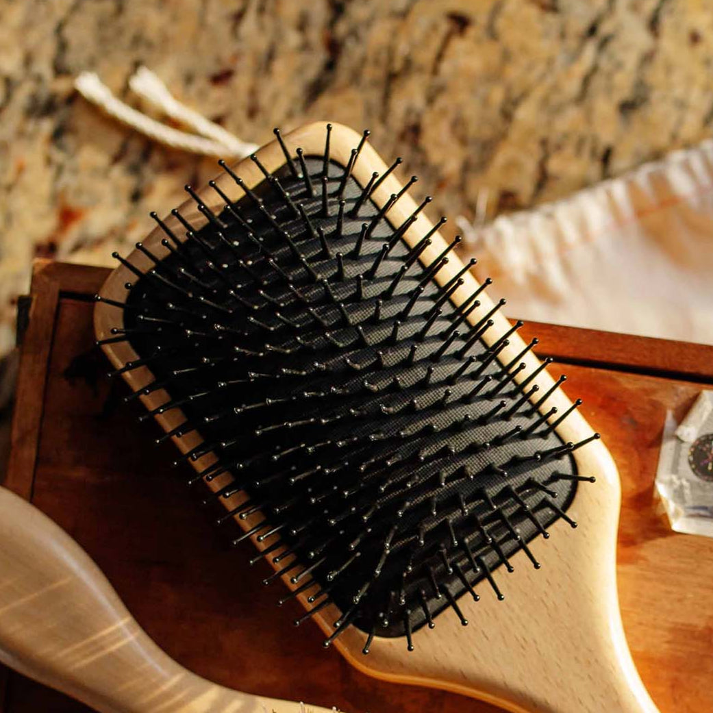 Wooden hairbrush with black bristles on a wooden surface.